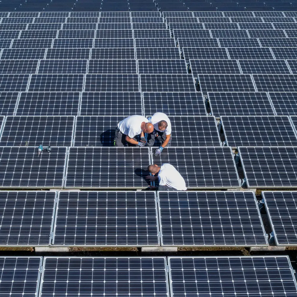 Luftaufnahme: Monteure auf einer großen PV-Dachanlage
