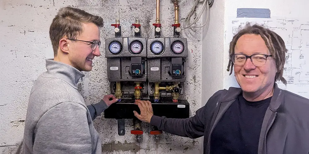 Zwei Mitarbeiter von Lebherz & Partner an einer Heizungsverteilung im Technikraum