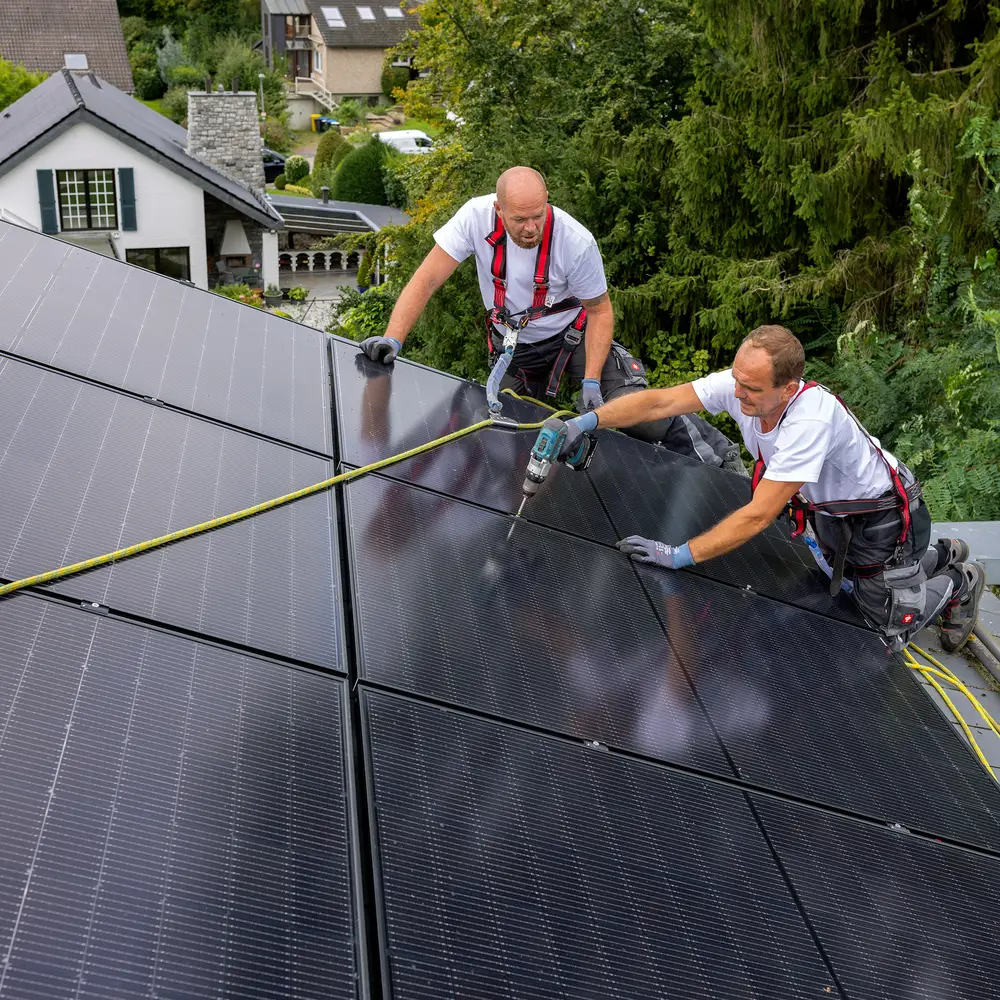 Monteur auf einem Dach mit Solarmodulen