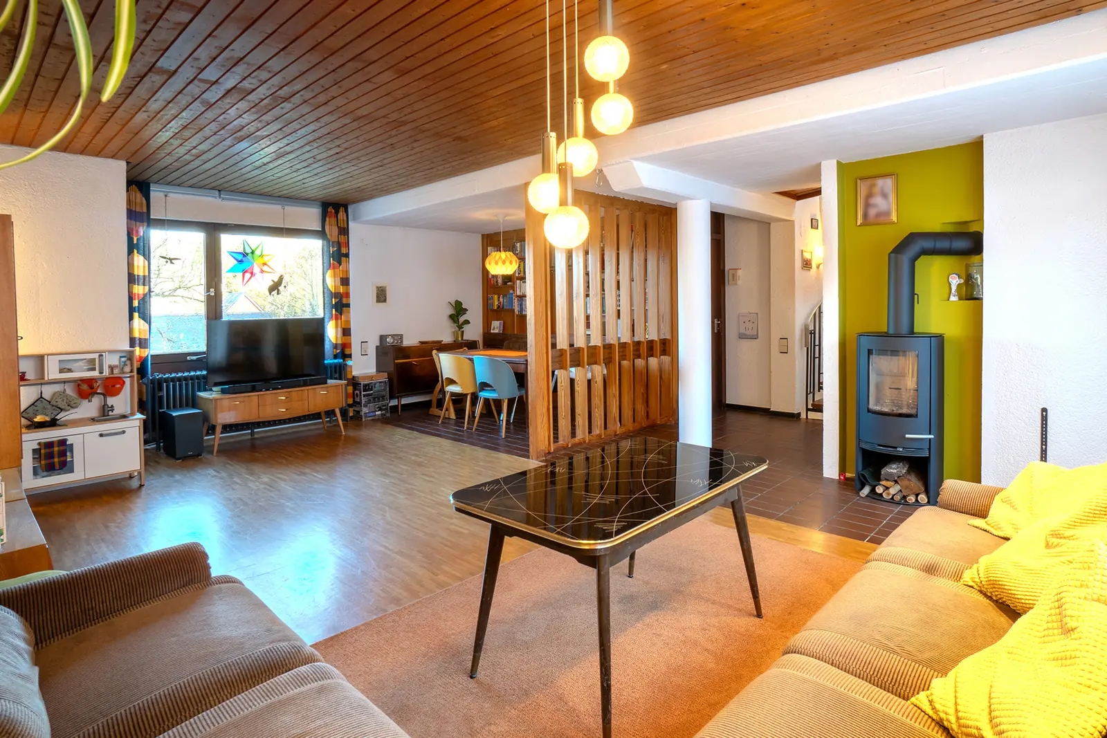 Helles Wohnzimmer mit Holzdecke und Kaminofen