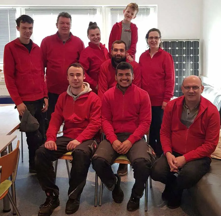 Das SOTECH-Team in roten Shirts vor einem Solarmodul